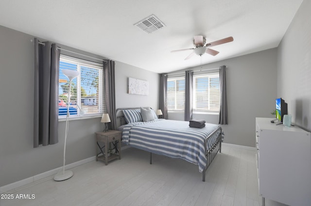 bedroom featuring light wood finished floors, visible vents, ceiling fan, and baseboards