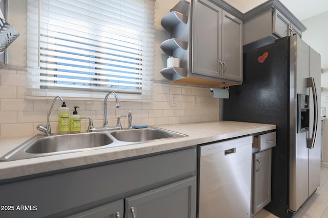 kitchen featuring gray cabinets, a sink, open shelves, tasteful backsplash, and dishwasher