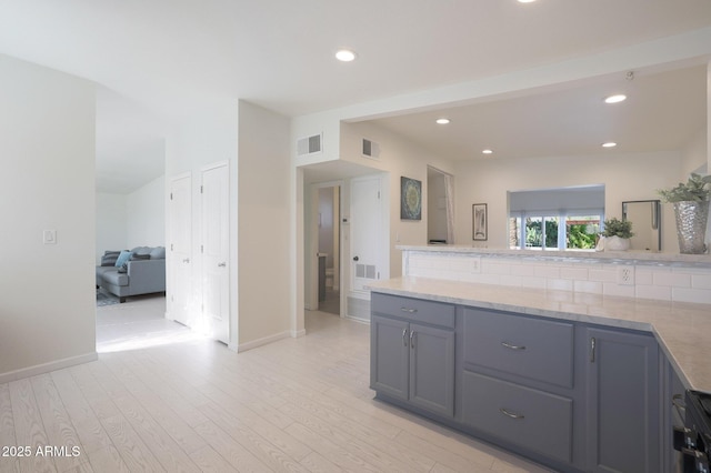 kitchen with light wood-type flooring, visible vents, a peninsula, and gray cabinets