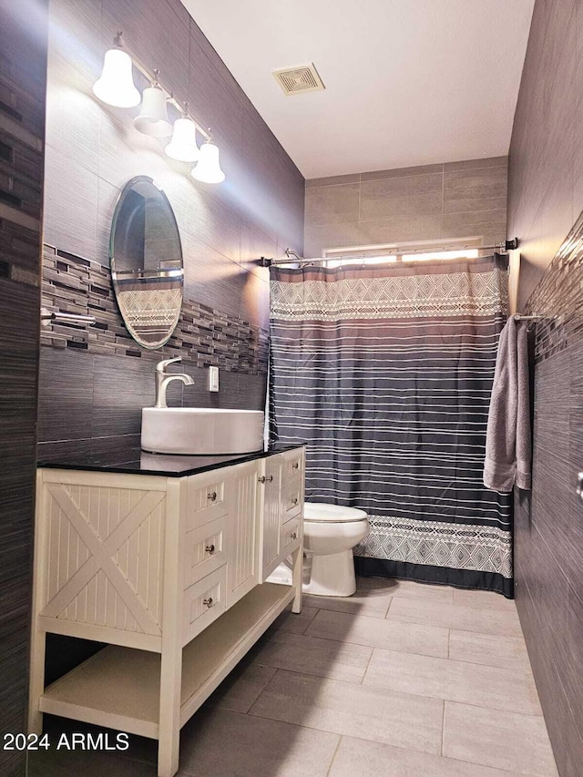 bathroom featuring toilet, vanity, tile walls, and walk in shower