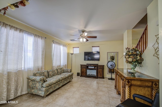 17374 W Adams St, Goodyear, AZ 85338 - living room featuring light tile patterned floors, ceiling fan, and stairs