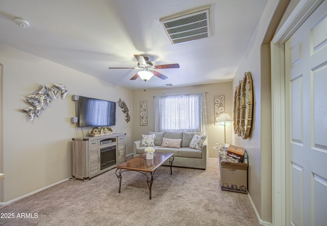 17374 W Adams St, Goodyear, AZ 85338 - living room with light colored carpet, visible vents, a fireplace, a ceiling fan, and baseboards