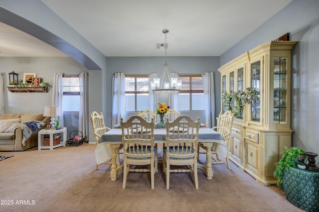 carpeted dining space featuring a chandelier