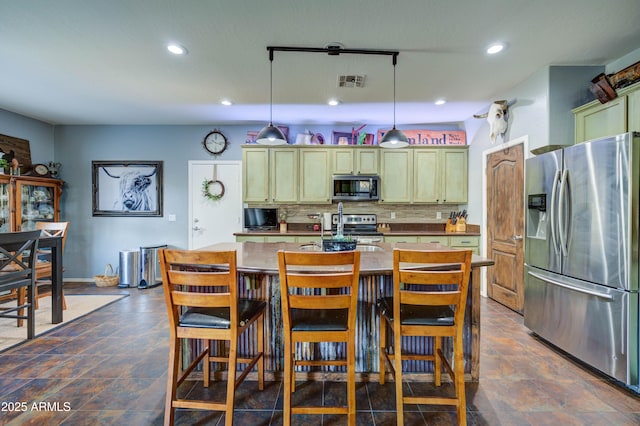 kitchen with tasteful backsplash, appliances with stainless steel finishes, decorative light fixtures, and sink