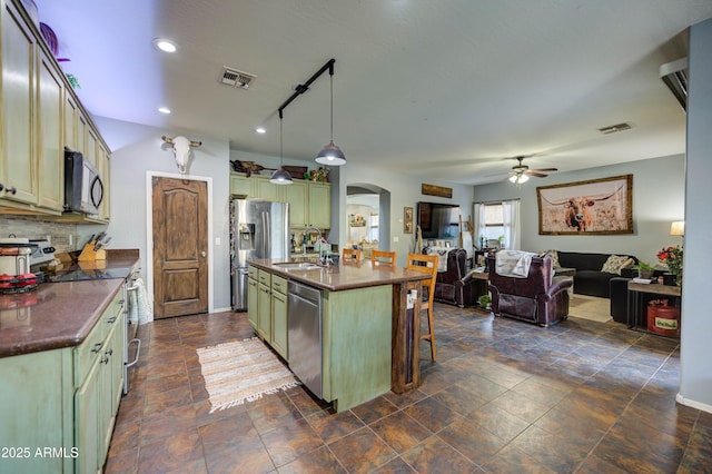 kitchen featuring appliances with stainless steel finishes, pendant lighting, an island with sink, backsplash, and a kitchen breakfast bar