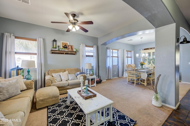 living room featuring ceiling fan with notable chandelier, a wealth of natural light, and carpet