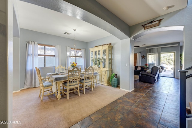 carpeted dining space with an inviting chandelier and plenty of natural light