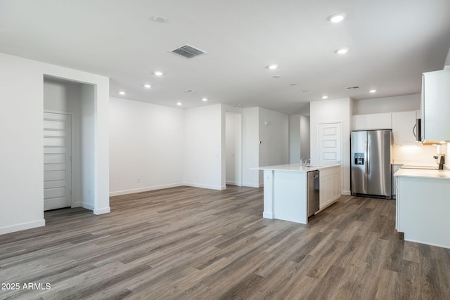 kitchen featuring sink, stainless steel appliances, wood-type flooring, an island with sink, and white cabinets