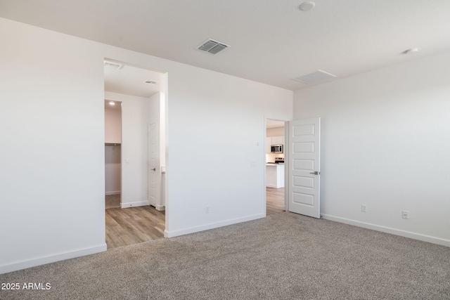 unfurnished bedroom with a walk in closet and light colored carpet