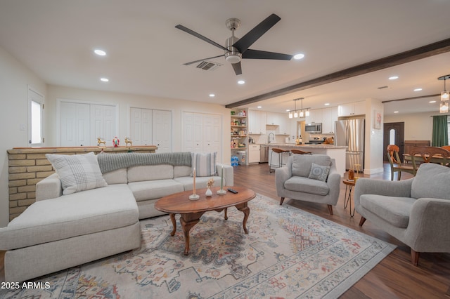 living room with beam ceiling, ceiling fan, and dark wood-type flooring