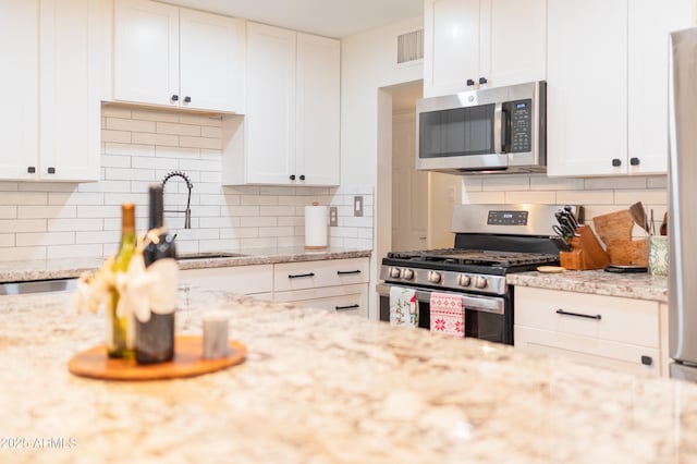 kitchen featuring backsplash, white cabinets, and appliances with stainless steel finishes