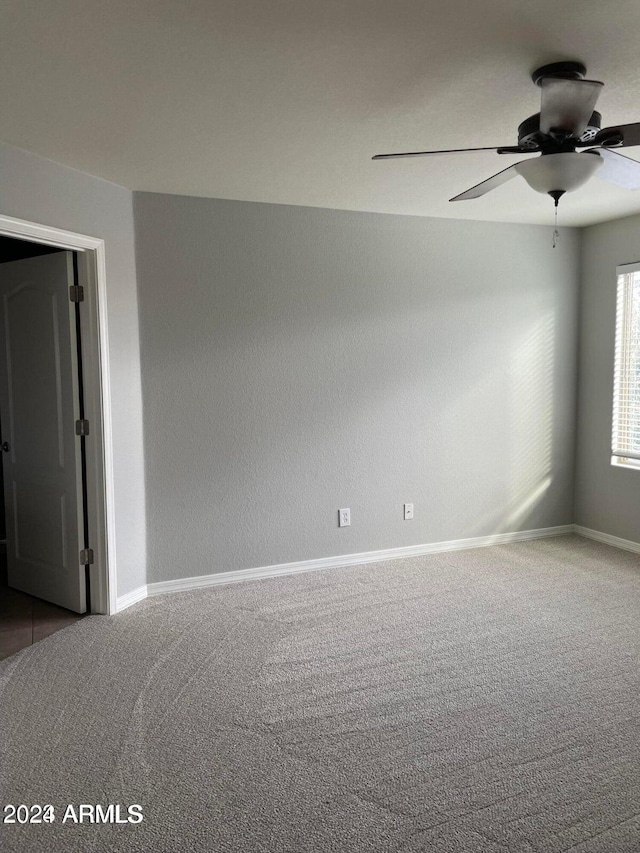 carpeted spare room featuring ceiling fan