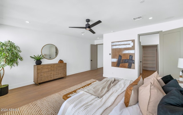 bedroom featuring a closet, a walk in closet, light wood-type flooring, and ceiling fan