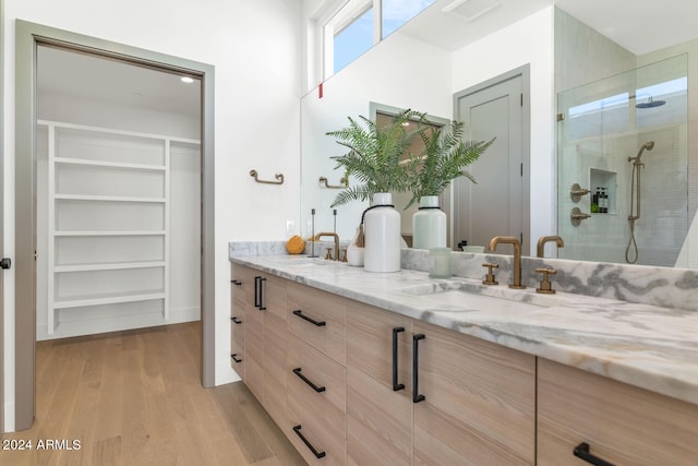 bathroom with wood-type flooring, a shower with door, and vanity