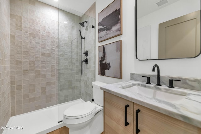 bathroom with vanity, tiled shower, and toilet