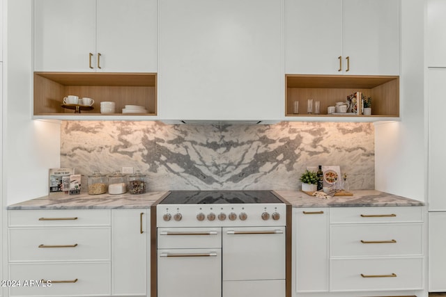 kitchen with light stone counters, white cabinetry, decorative backsplash, and white stove