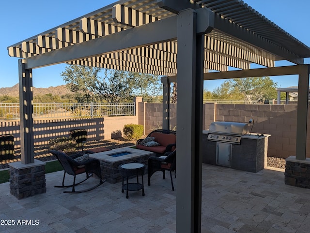 view of patio / terrace with an outdoor kitchen, grilling area, a pergola, a mountain view, and a fire pit