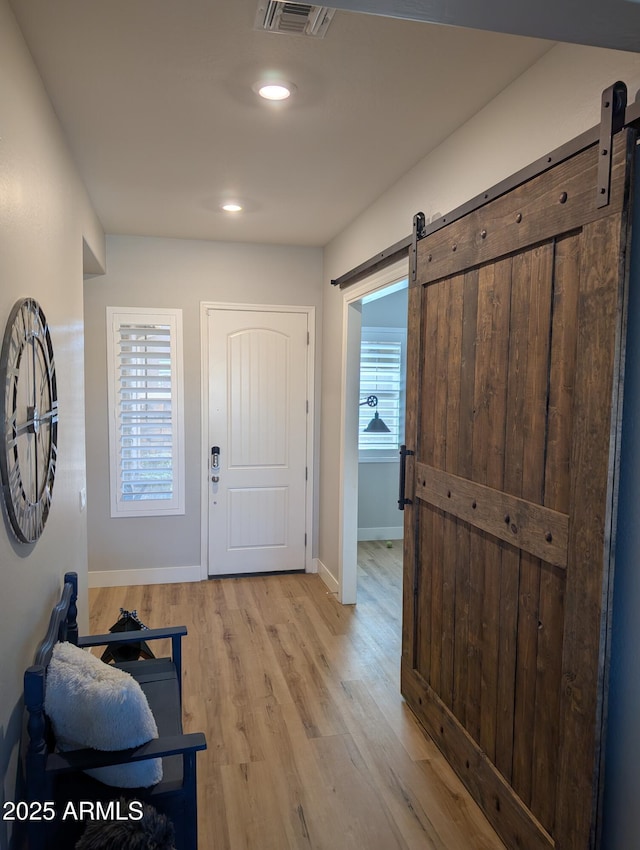 entryway featuring a healthy amount of sunlight, a barn door, and light hardwood / wood-style flooring