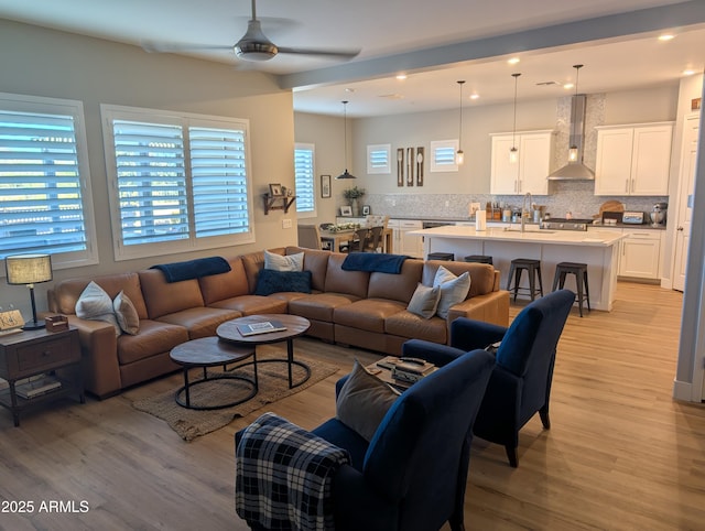 living room with sink, ceiling fan, and light hardwood / wood-style flooring