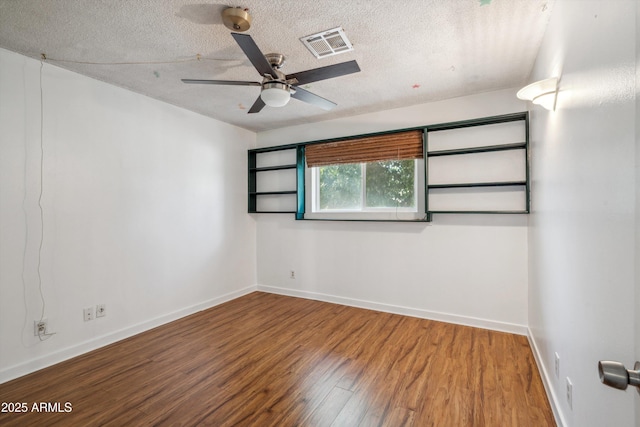 spare room featuring wood finished floors, a textured ceiling, a ceiling fan, and baseboards