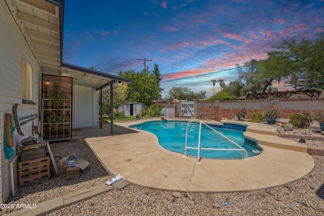 view of pool featuring a patio, a fenced backyard, a shed, and an outdoor structure