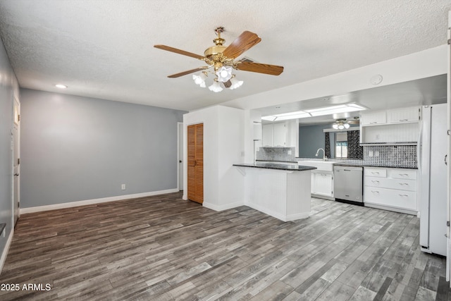 kitchen featuring dishwasher, a ceiling fan, a textured ceiling, wood finished floors, and decorative backsplash