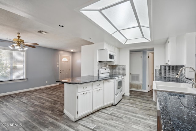 kitchen featuring white appliances, a sink, white cabinets, light wood-style flooring, and backsplash