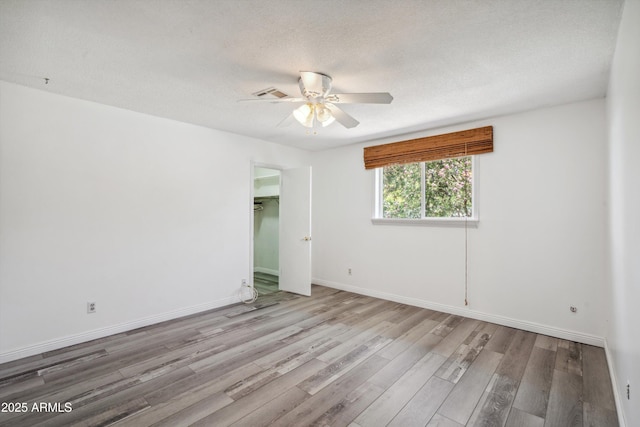 unfurnished room with ceiling fan, wood finished floors, a textured ceiling, and baseboards