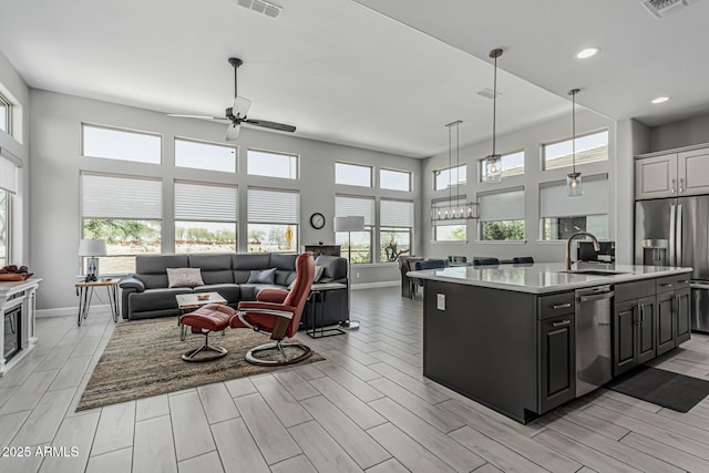 kitchen featuring a sink, open floor plan, ceiling fan, light countertops, and appliances with stainless steel finishes