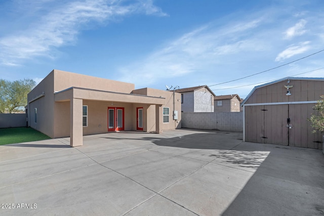 rear view of property with a patio area and a storage shed