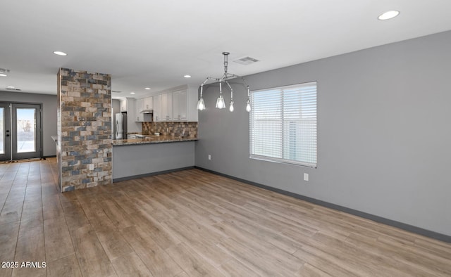 unfurnished living room with light hardwood / wood-style floors and french doors