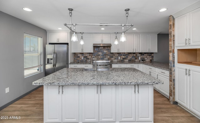 kitchen featuring white cabinetry, stainless steel appliances, and a center island with sink