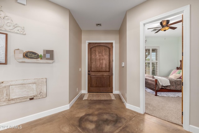 foyer with ceiling fan and concrete flooring