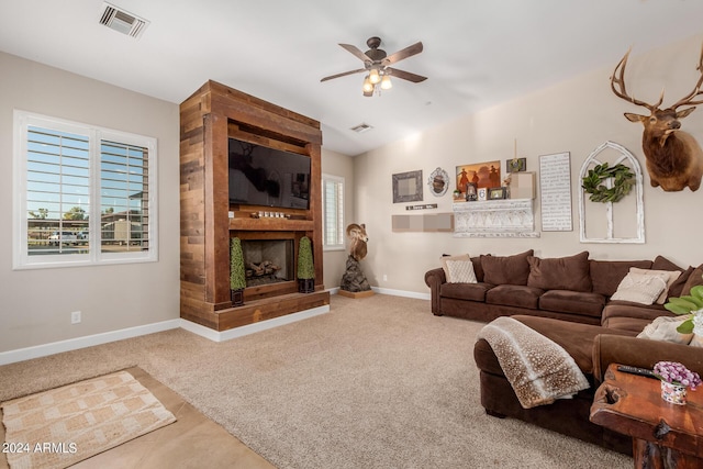 living room with ceiling fan, a large fireplace, a healthy amount of sunlight, and carpet floors