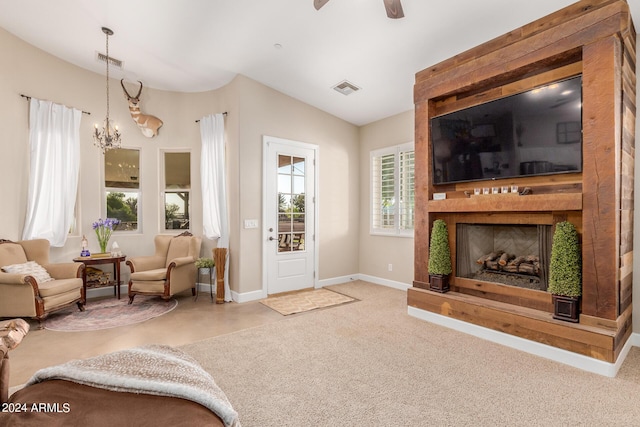 carpeted living room with lofted ceiling and ceiling fan with notable chandelier