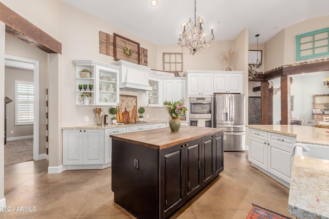 kitchen featuring wooden counters, premium range hood, stainless steel appliances, a center island, and white cabinets