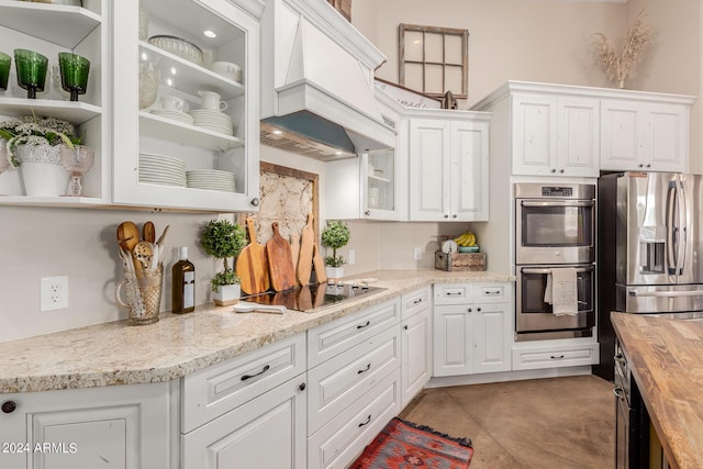 kitchen featuring white cabinets, appliances with stainless steel finishes, custom range hood, and wooden counters