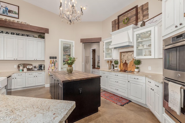 kitchen featuring stainless steel appliances, premium range hood, a center island, and white cabinets