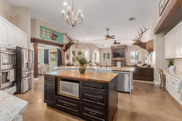 kitchen featuring butcher block counters, sink, white cabinets, a center island, and stainless steel appliances