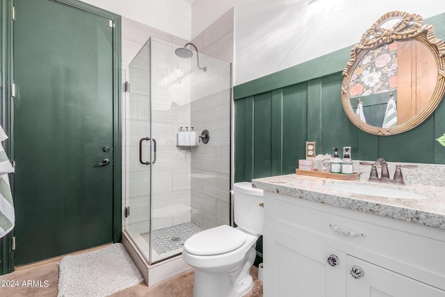 bathroom with vanity, a shower with door, and toilet