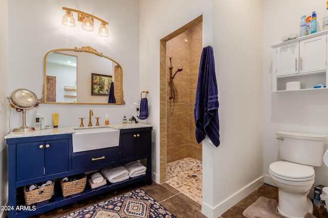 bathroom featuring a tile shower, vanity, tile patterned flooring, and toilet