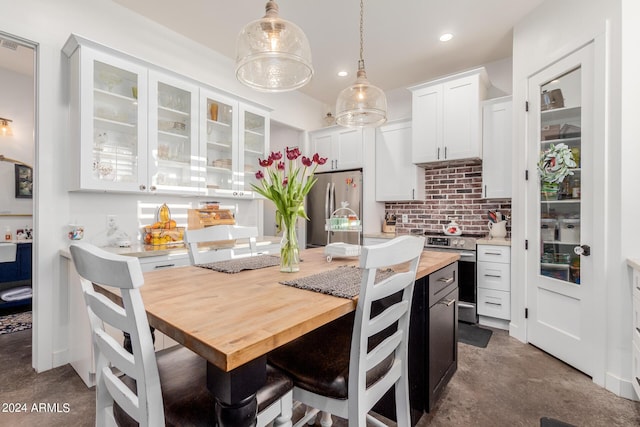 kitchen featuring appliances with stainless steel finishes, decorative light fixtures, white cabinetry, decorative backsplash, and a center island