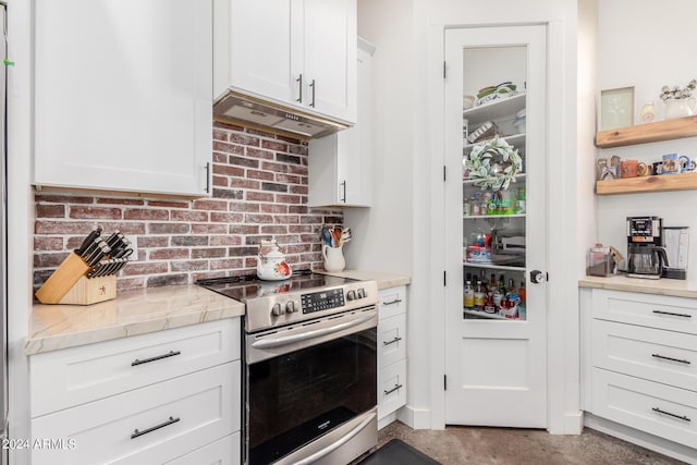 kitchen with light stone counters, stainless steel range with electric cooktop, and white cabinets