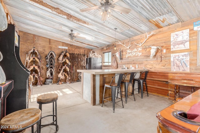 bar featuring wooden walls, stainless steel fridge, ceiling fan, and vaulted ceiling