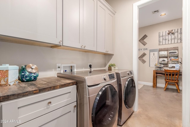 clothes washing area with cabinets and washer and clothes dryer