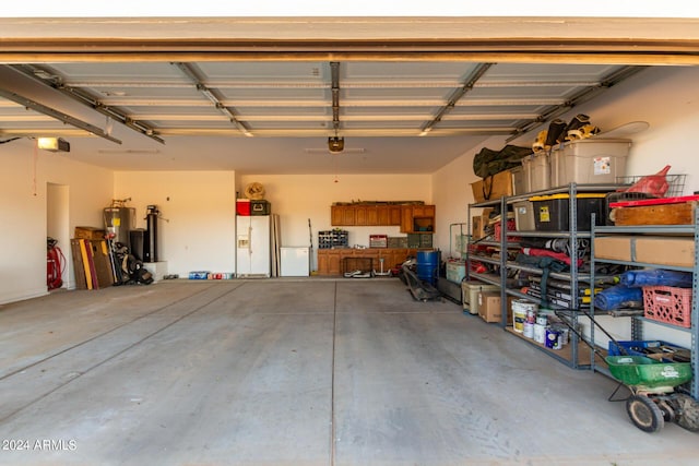 garage featuring a garage door opener, gas water heater, and white fridge with ice dispenser