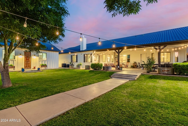 back house at dusk with a yard and a patio