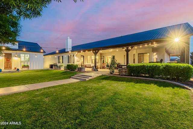 back house at dusk with a lawn