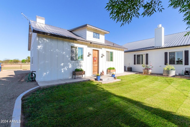 rear view of house with a yard, central AC unit, and a patio area