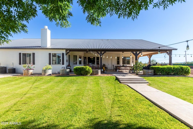 rear view of property featuring a patio, central AC, and a lawn